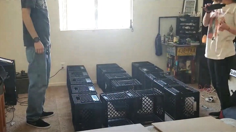 Couple building bedframe out of black milk crates in small bedroom