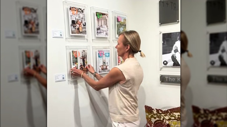 Woman hanging up framed Architectural Digest magazines in clear frames