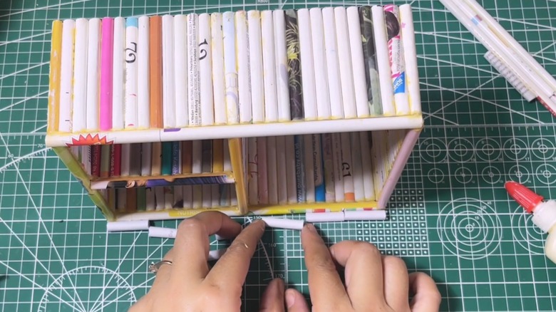 Rolled up magazine pages as sides for DIY organizer on craft table