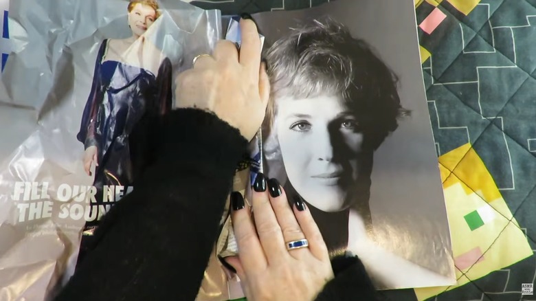 Woman crumpling magazine pages atop geometric bedspread