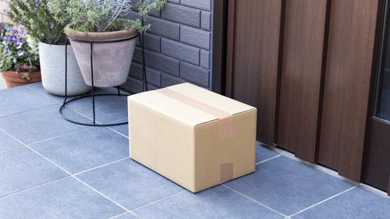 Cardboard box on front porch with gray tile.