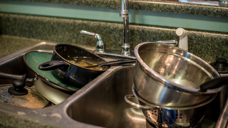 Kitchen sink full of dirty pots and pans.