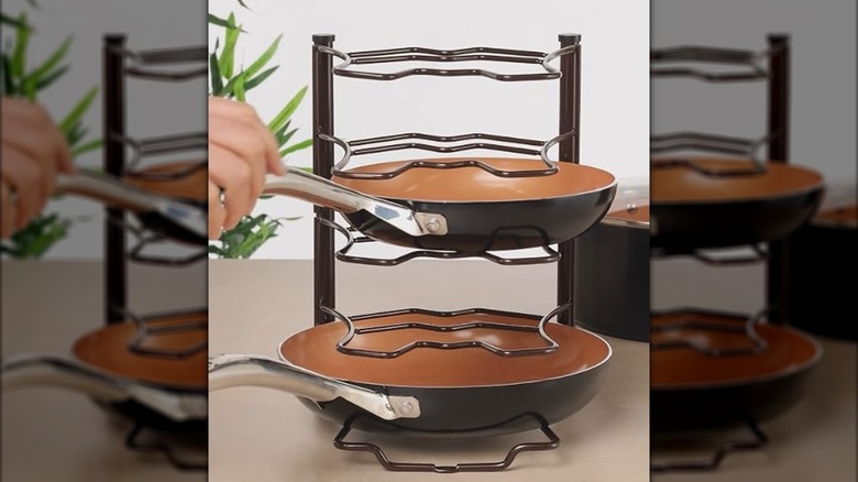 A pan being placed onto a Deco Brothers Pan Organizer Rack on a kitchen counter