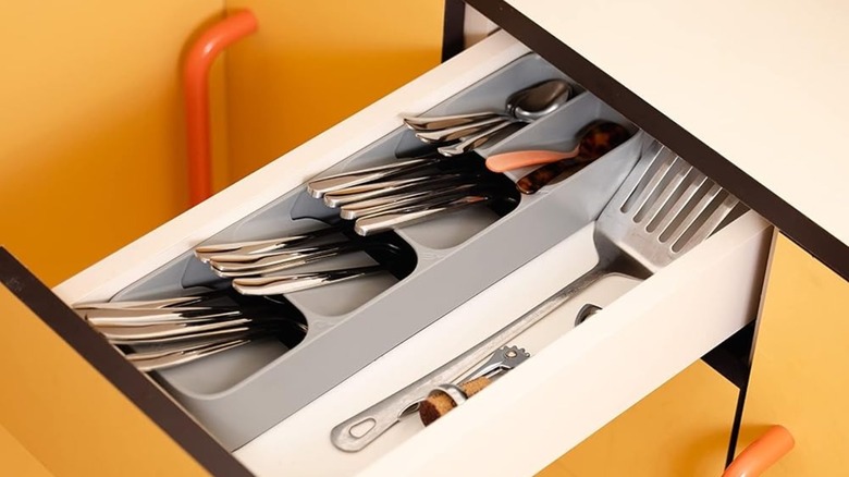 A Joseph Joseph DrawerStore Compact Utensil Organizer in a narrow kitchen drawer
