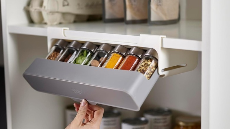 A Joseph Joseph Under-Shelf Cabinet Spice Rack Organizer installed on a kitchen shelf