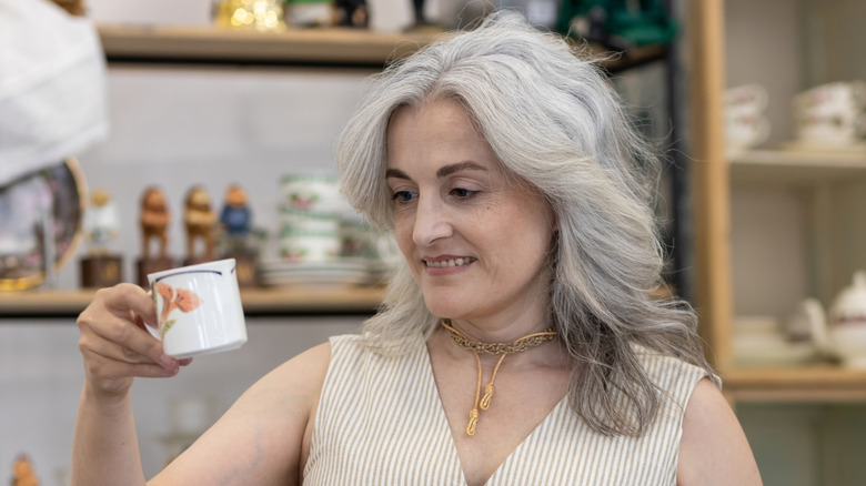 Woman in a thrift store examing a tea cup