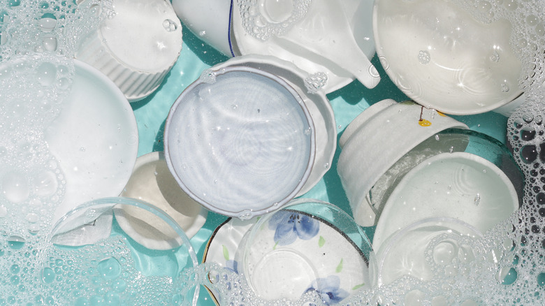 white dishes soaking in soapy water