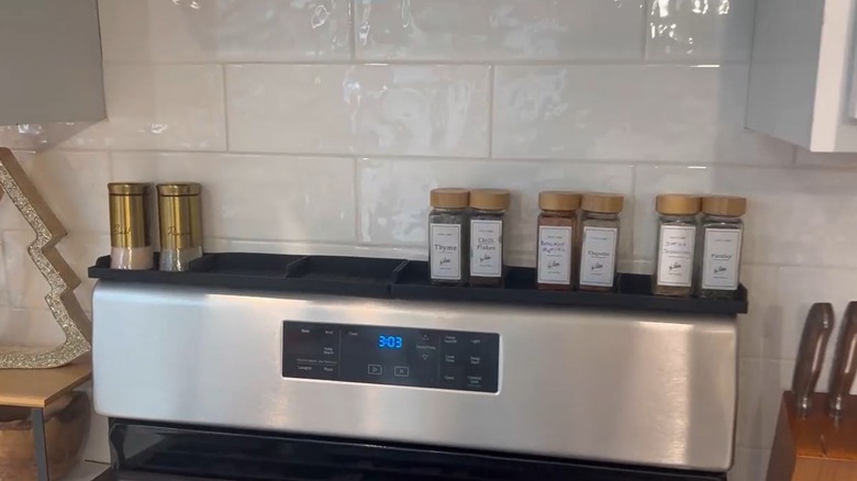 A long magnetic shelf holding spices and seasonings on a stovetop