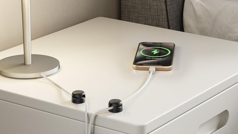 Black small cord organizers on a nightstand for organized phone charger and lamp cord