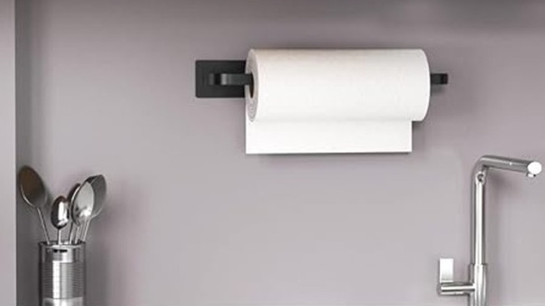 A slim black paper towel holder in a kitchen
