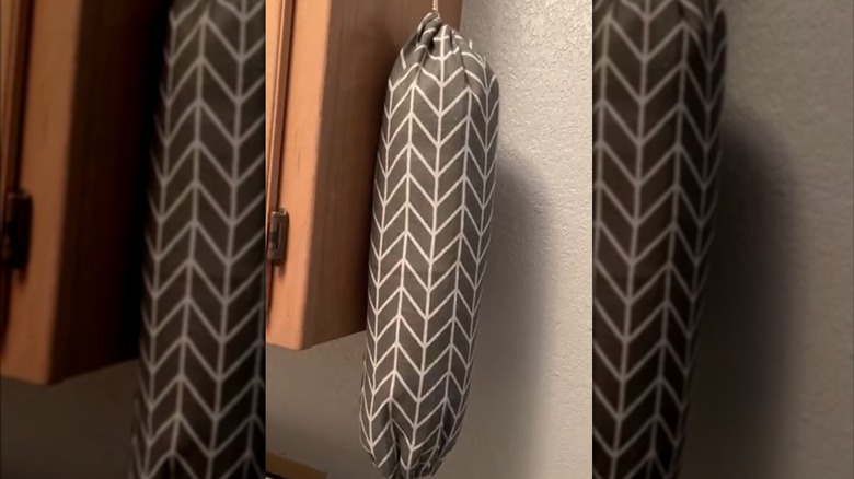 Two plastic bag holders hanging from wall-mounted hooks in a bedroom