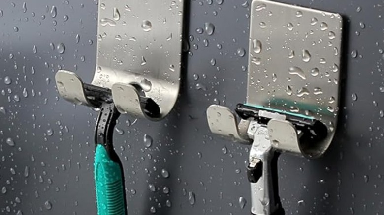 Razors hooked on stainless steel holders with drops of water on them