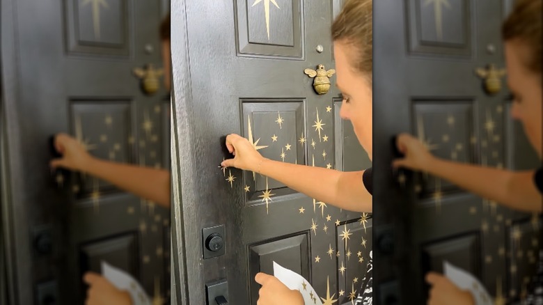 Woman pinning gold star peel-and-stick stickers to front door