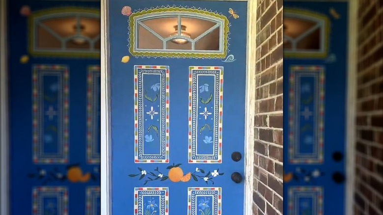 Front door painted blue with flowers, fruits, and shells for whimsical touch