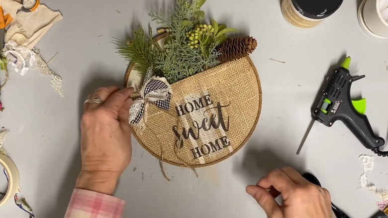 Woman designing welcome sign with burlap and artificial greenery for front door