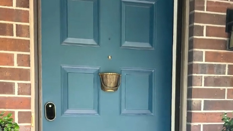 Front door painted blue with antique basket-style brass knocker