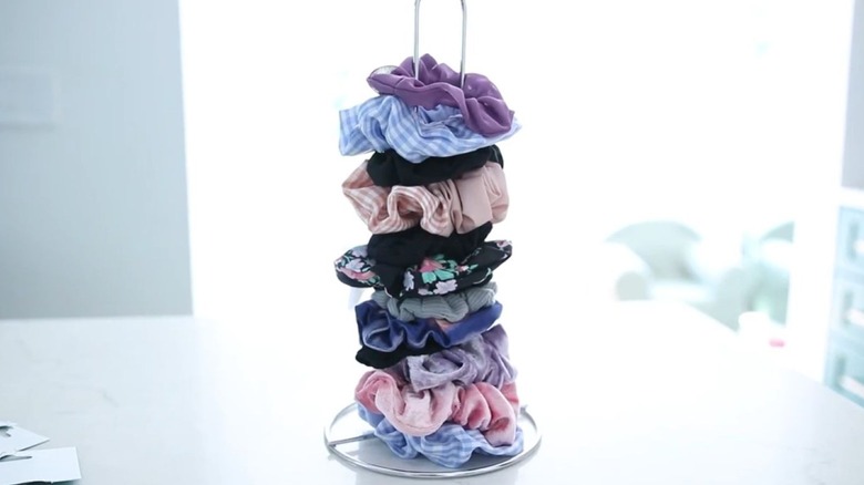 Paper towel holder with hair ties stacked on it