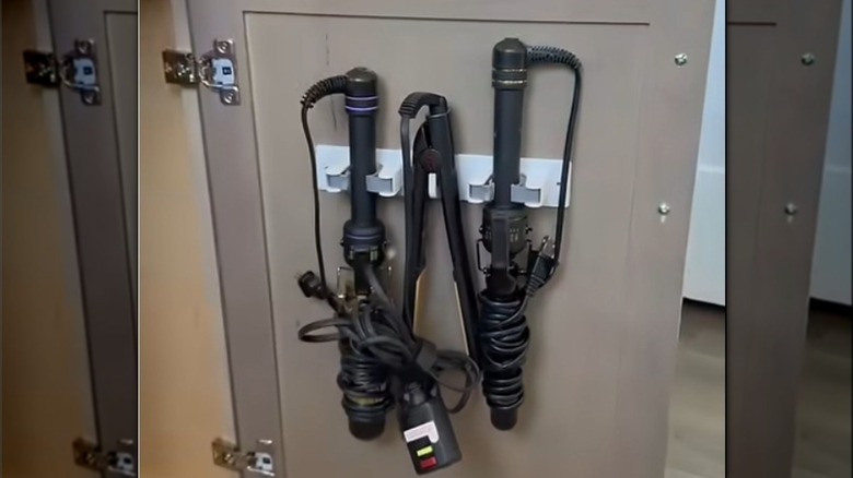 Hair tools mounted on a broom holder inside a cabinet