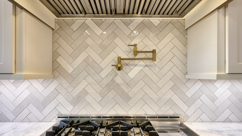 Pot filler installed on the wall above a gas cooktop