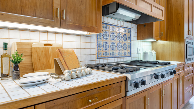 Kitchen with dated white tile countertops and backsplash