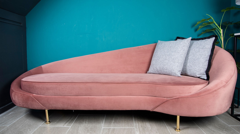 A round pink couch in a teal room