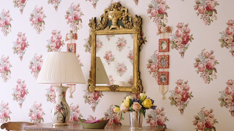 Rose print wallpaper surrounding a decorative mirror