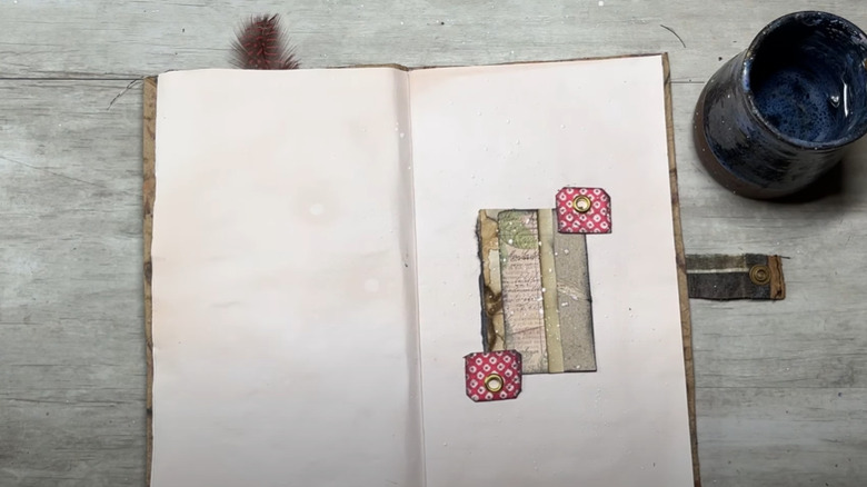 A scrapbook opened to a page with a piece held down by two DIY photo corners.