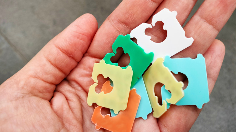A hand holding a set of colorful bread tags.