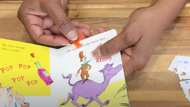 Hands placing a bread tag on a page of a children's book.