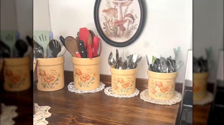 Classic cozy kitchen with matching utensil crocks on round doilies on wood surface