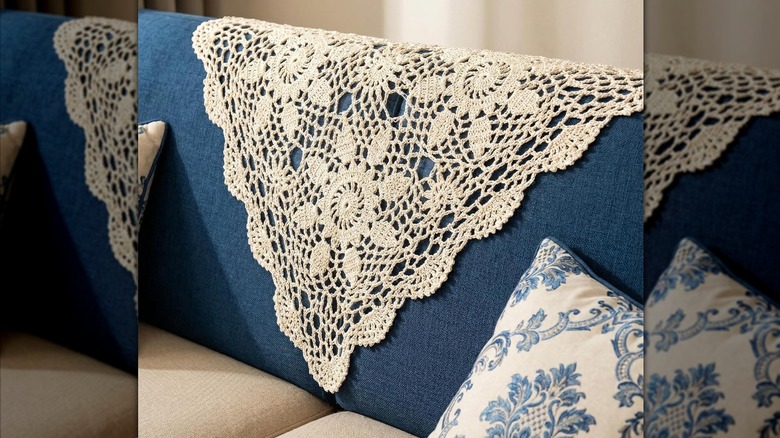 Blue and beige denim couch with square-shaped doily angled over center cushion