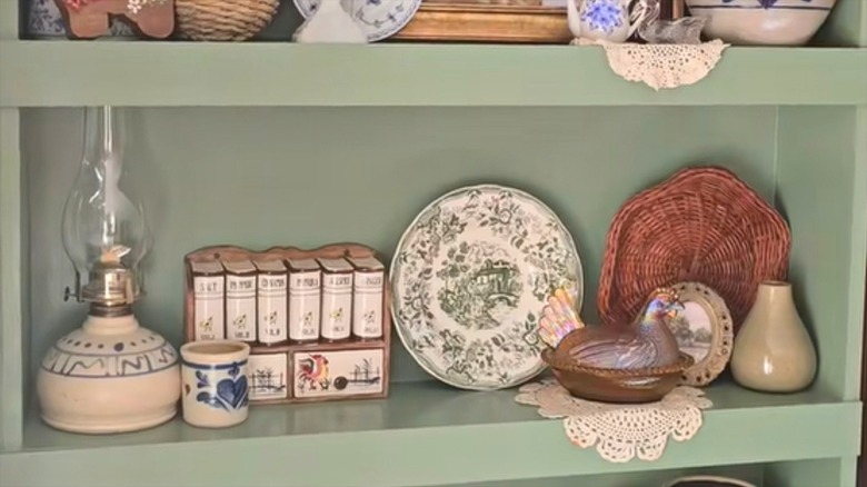 Circular doilies dangling off sage green shelf with vintage kitschy decor