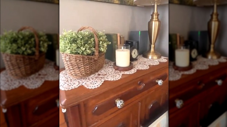 Long lacy doily sprawled across vintage wood cabinet with classic decor