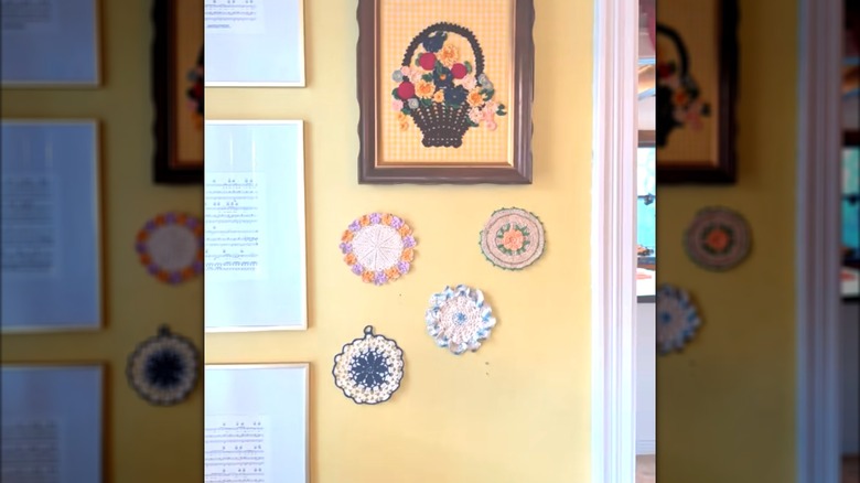 Mini round doilies with colorful patterns pinned to yellow wall beside framed decor