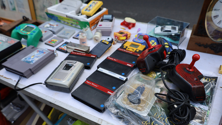 A table at a flea market full of vintage video games and video game systems