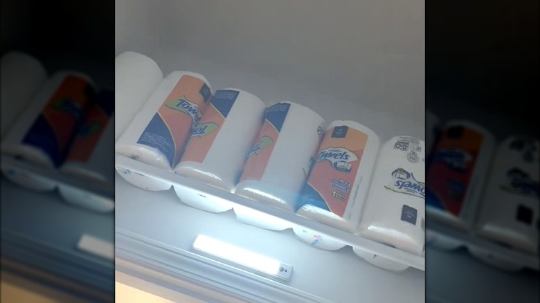 Paper towels stored above room door with bar light on white curtain rod