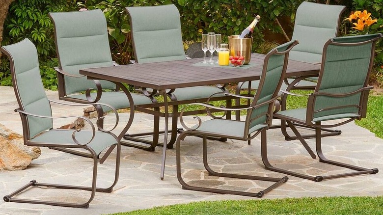 Six green chairs arranged around a rectangular table on a patio