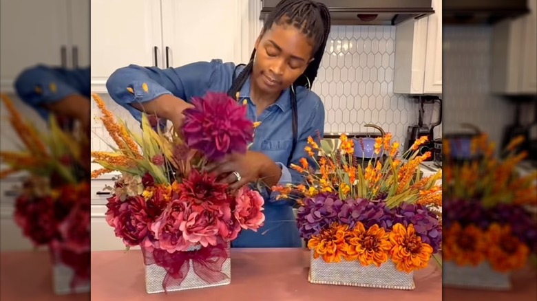 Young woman arranging artificial flowers in DIY cardboard box planters.