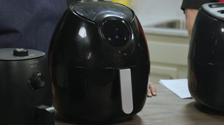 Three black air fryers in a row on a table