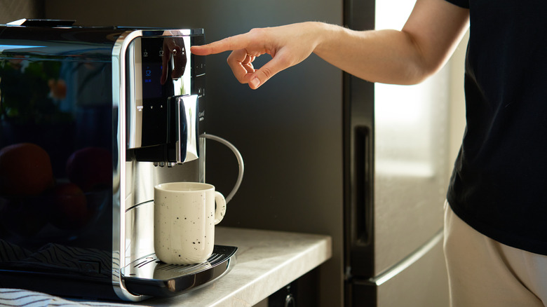Person turning on a coffee maker