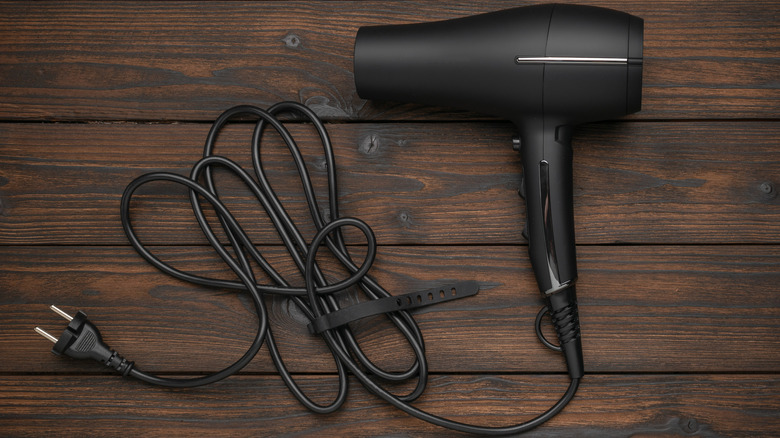 A black hair dryer on a wooden surface