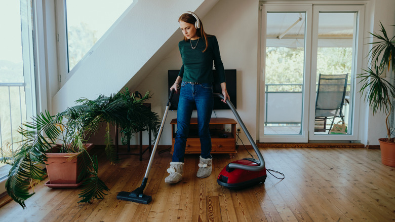 Young woman vacuuming the living room with a corded vacuum cleaner
