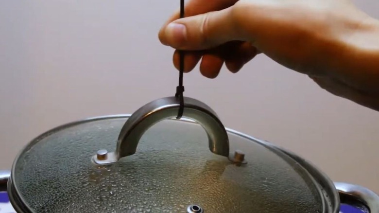 Person lifting pot lid with zip tie