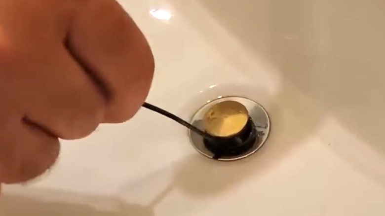 Man unclogging drain with zip tie