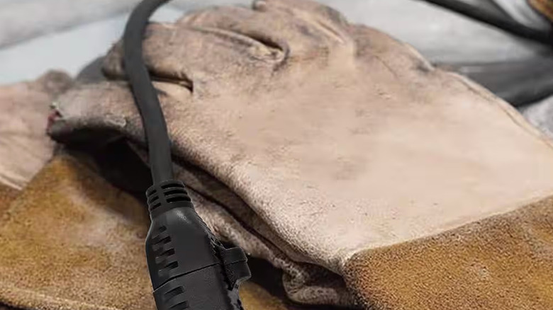 A black extension cord lays on a pair of dirty work gloves
