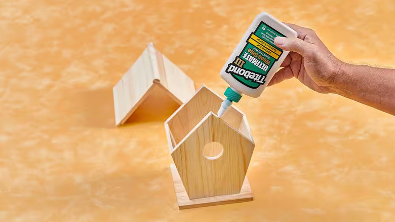 A person uses Titebond Wood Glue on a wooden birdhouse