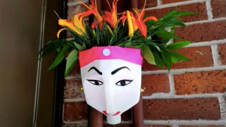 An upside-down milk jug planter with a face