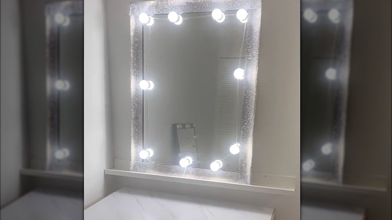White glam vanity mirror with LED lighting and picture ledge shelf above table