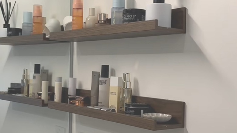 Cluttered bathroom IKEA shelves against mirror on wall with various products