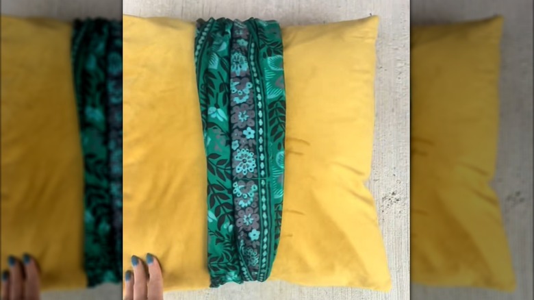 Yellow throw pillow wrapped in green floral scarf accent
